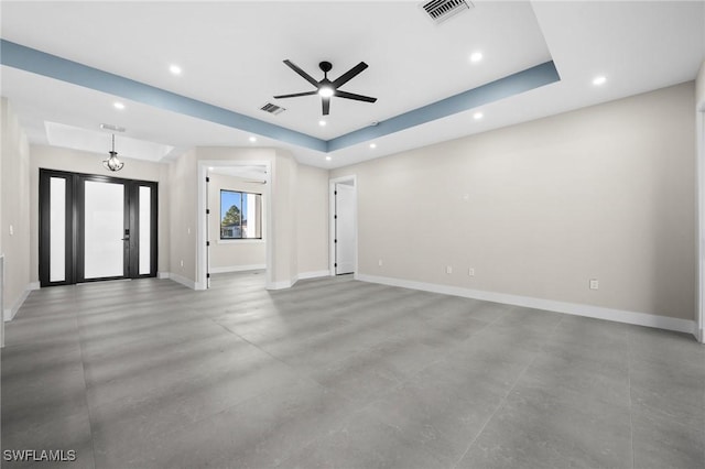 unfurnished living room featuring a tray ceiling and ceiling fan