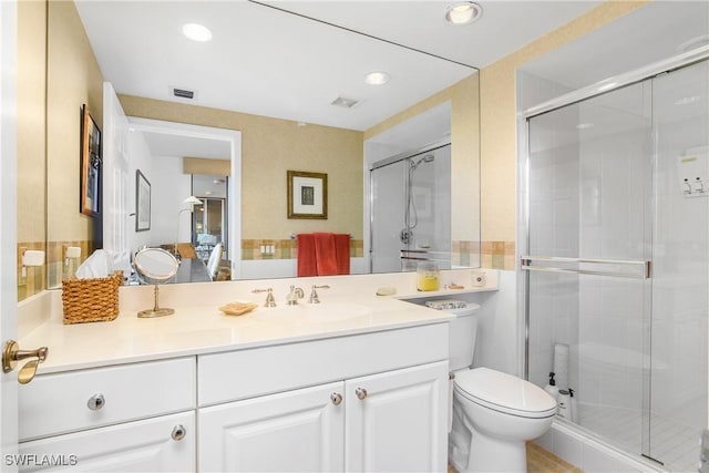 bathroom featuring vanity, toilet, and a shower with door