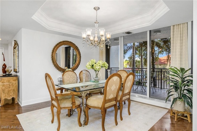 dining area featuring a raised ceiling, dark hardwood / wood-style flooring, ornamental molding, and an inviting chandelier