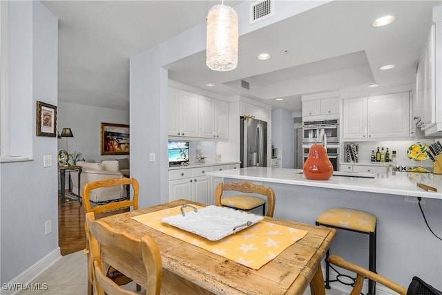 dining area with a raised ceiling and light tile patterned floors