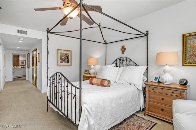 bedroom featuring light carpet, ensuite bathroom, and ceiling fan