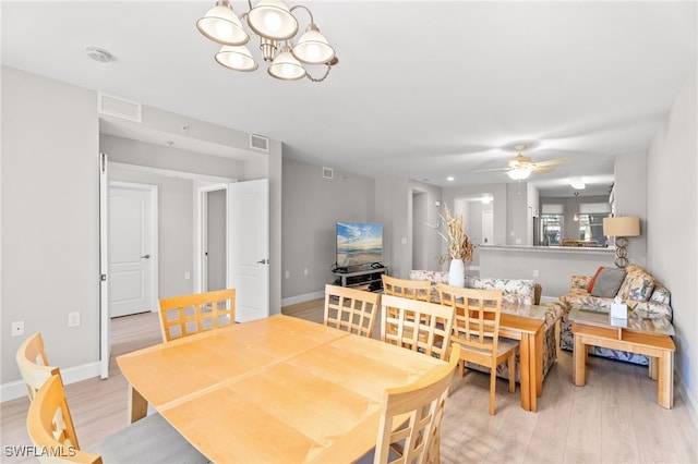 dining space with ceiling fan with notable chandelier and light wood-type flooring