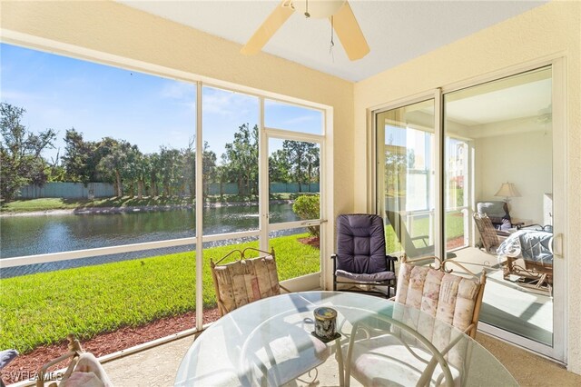 sunroom / solarium featuring ceiling fan and a water view