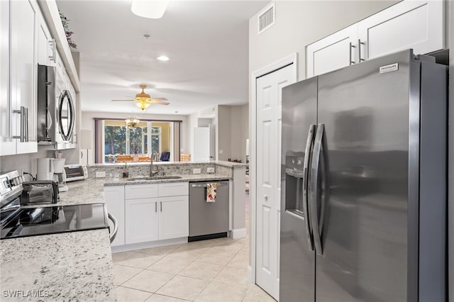 kitchen featuring light stone countertops, appliances with stainless steel finishes, sink, light tile patterned floors, and white cabinetry