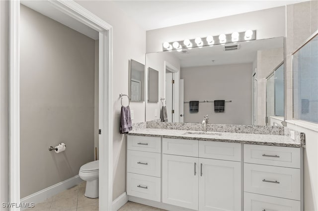 bathroom featuring tile patterned floors, vanity, toilet, and a shower with door