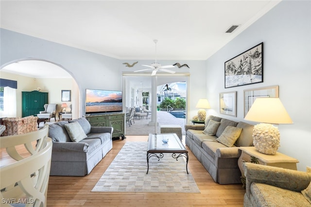 living room with ceiling fan, ornamental molding, and light wood-type flooring