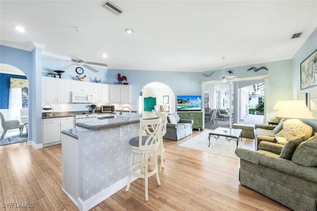 kitchen featuring white cabinetry, light hardwood / wood-style flooring, white appliances, a breakfast bar, and ornamental molding