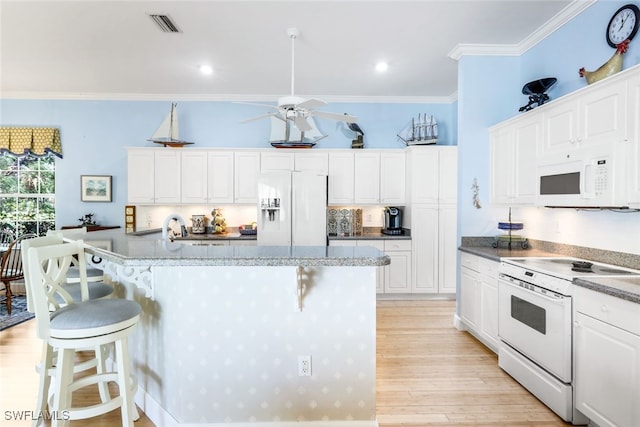 kitchen with a breakfast bar, white appliances, ornamental molding, light hardwood / wood-style floors, and white cabinetry