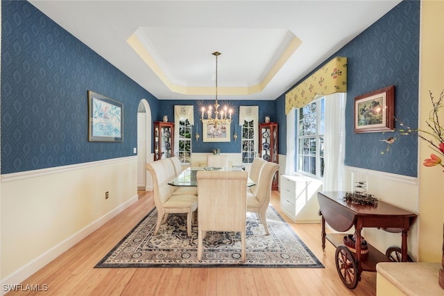 dining space featuring a tray ceiling, wood-type flooring, and an inviting chandelier