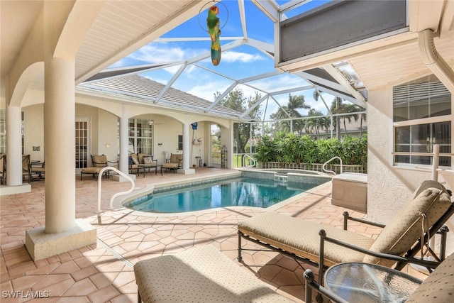 view of pool featuring glass enclosure, an in ground hot tub, and a patio area