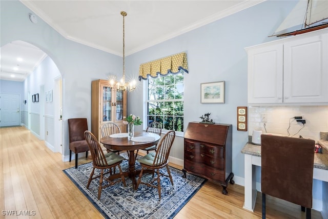 dining area featuring light wood-type flooring, crown molding, and a chandelier