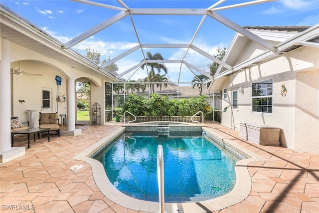 view of pool featuring glass enclosure, an in ground hot tub, an outdoor hangout area, and a patio