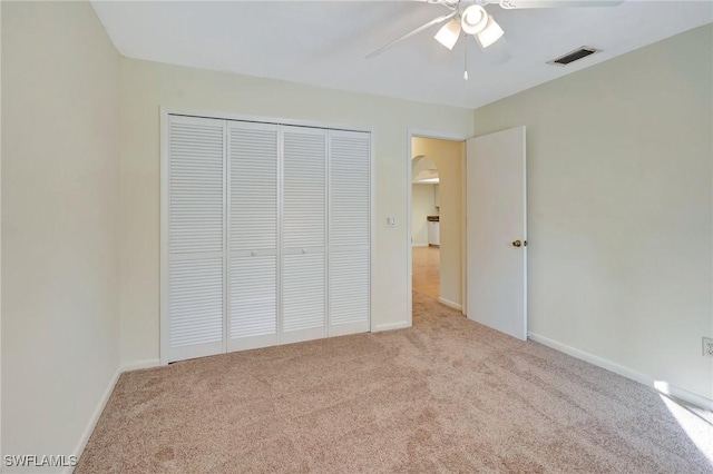 unfurnished bedroom with ceiling fan, a closet, and light colored carpet