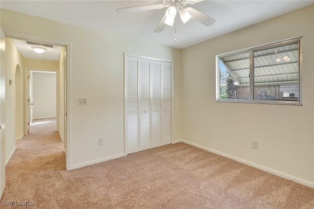 unfurnished bedroom with ceiling fan, light colored carpet, and a closet