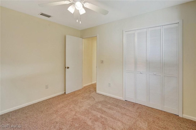 unfurnished bedroom with ceiling fan, a closet, and light colored carpet