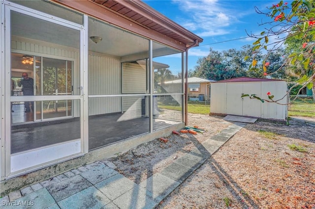 view of patio featuring a sunroom and a storage unit