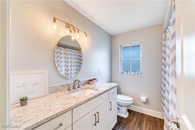 bathroom featuring vanity, baseboards, toilet, and wood finished floors