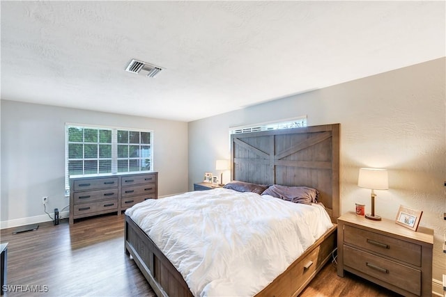 bedroom with a textured ceiling and dark hardwood / wood-style floors