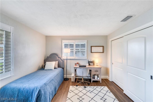 bedroom with a textured ceiling, a closet, and dark hardwood / wood-style floors