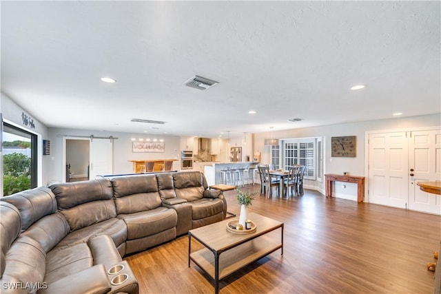 living room with a barn door and light wood-type flooring