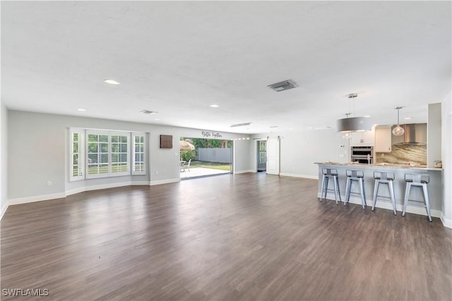 unfurnished living room with visible vents, plenty of natural light, and dark wood finished floors