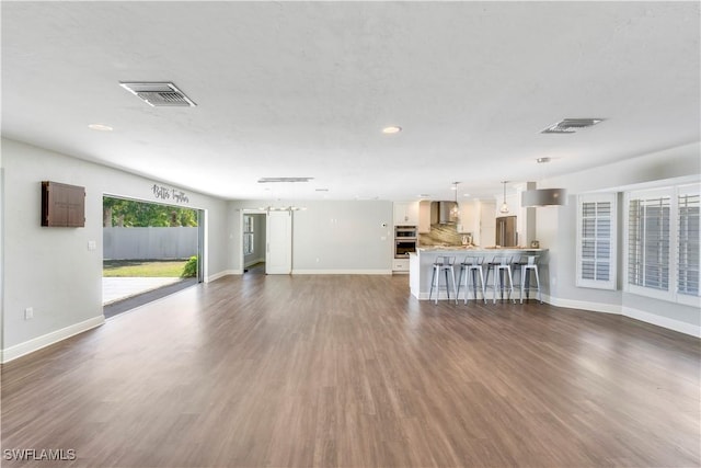 unfurnished living room with visible vents, baseboards, recessed lighting, and wood finished floors