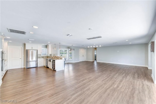 unfurnished living room featuring visible vents, baseboards, and recessed lighting