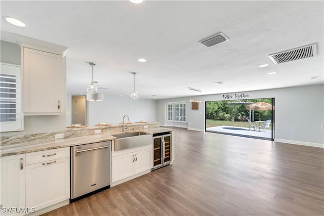 kitchen featuring visible vents, dishwasher, a sink, open floor plan, and beverage cooler