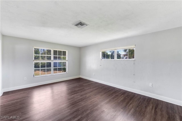 spare room featuring visible vents, baseboards, and wood finished floors