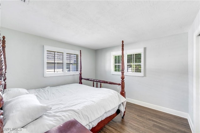 bedroom featuring baseboards, multiple windows, and wood finished floors