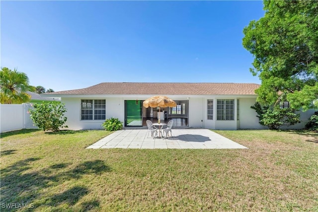 rear view of house featuring a patio area, stucco siding, fence, and a lawn