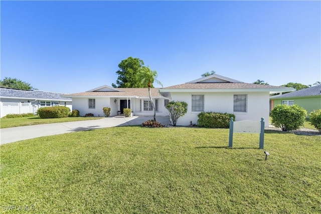 ranch-style house with concrete driveway, a front yard, and fence