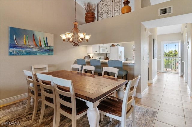 dining room with light tile patterned floors, a notable chandelier, and a high ceiling