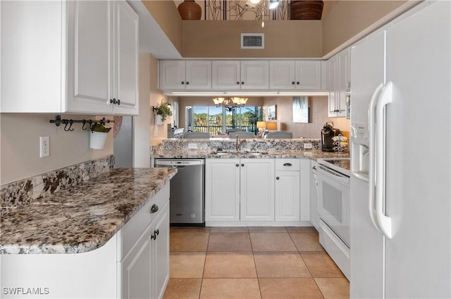 kitchen with white appliances, sink, light tile patterned floors, an inviting chandelier, and white cabinetry