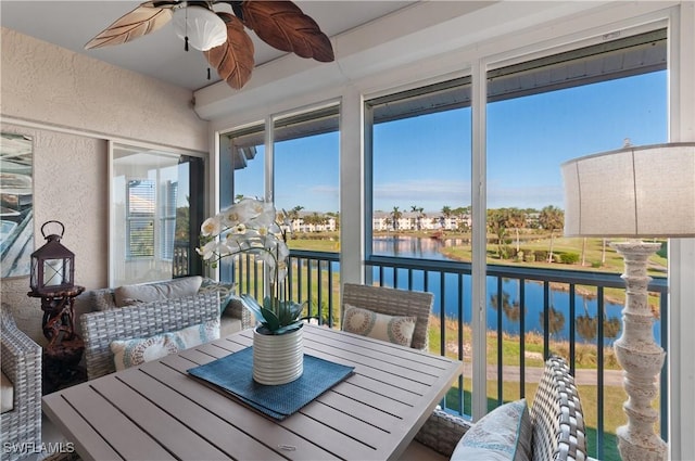 sunroom / solarium featuring a water view and ceiling fan