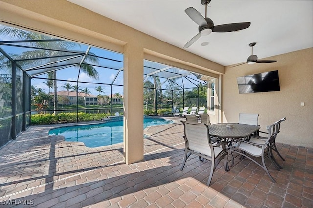 view of pool featuring glass enclosure, ceiling fan, and a patio area