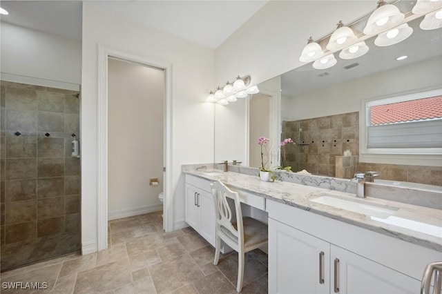 bathroom with tiled shower, vanity, and toilet