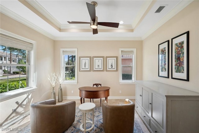 living area featuring a raised ceiling, crown molding, ceiling fan, and a healthy amount of sunlight