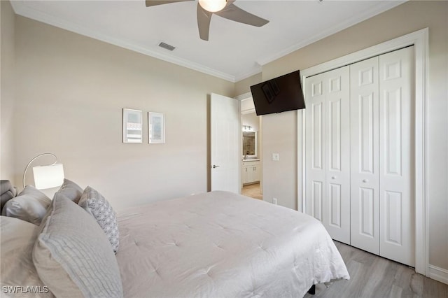 bedroom featuring ceiling fan, light hardwood / wood-style floors, crown molding, and a closet