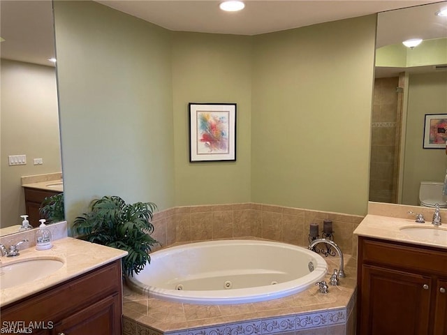 bathroom with tiled tub, vanity, and toilet