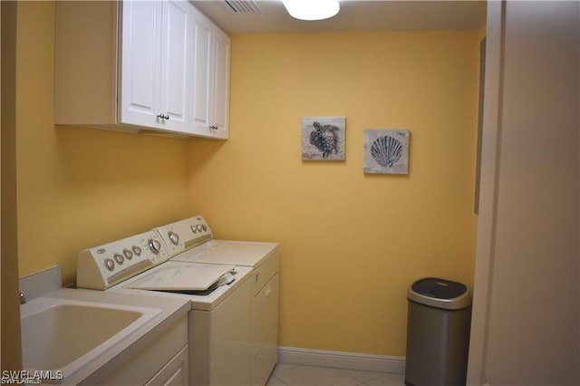 laundry area featuring washer and clothes dryer, light tile patterned floors, and cabinets