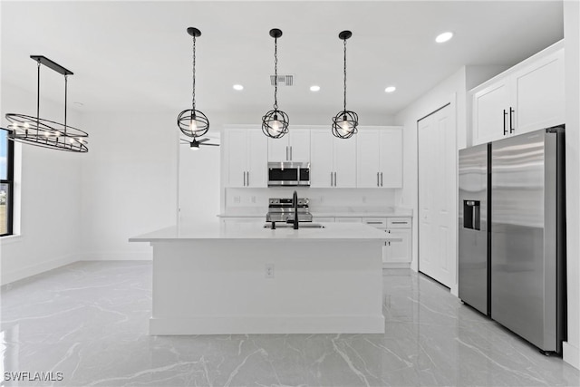 kitchen featuring appliances with stainless steel finishes, a kitchen island with sink, sink, white cabinetry, and hanging light fixtures