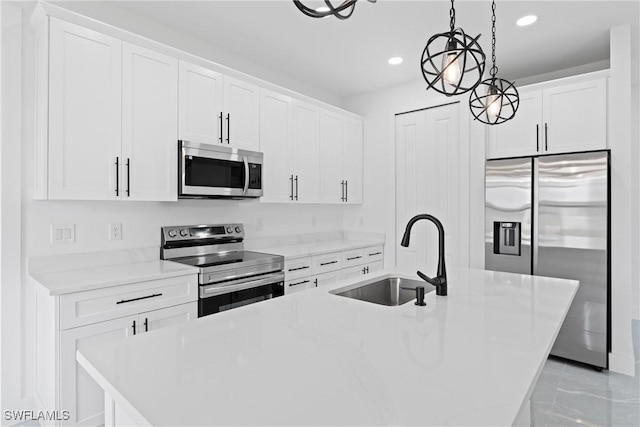 kitchen with a kitchen island with sink, hanging light fixtures, sink, white cabinetry, and stainless steel appliances