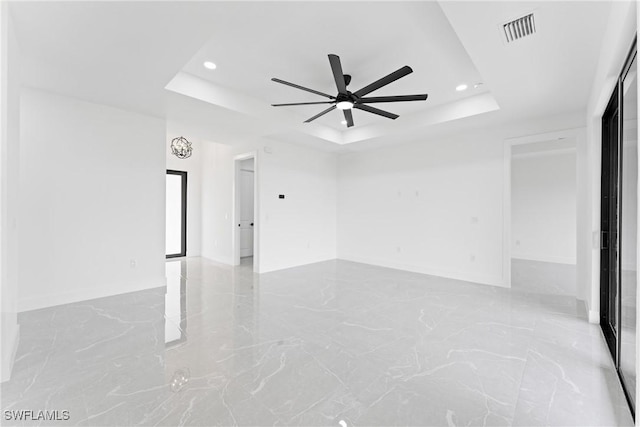 spare room with a raised ceiling and ceiling fan