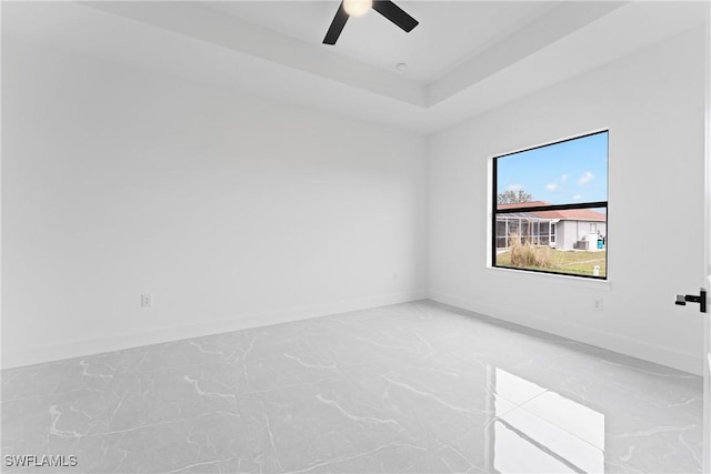 empty room featuring a tray ceiling and ceiling fan