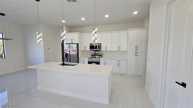 kitchen with white cabinets, appliances with stainless steel finishes, pendant lighting, and an island with sink