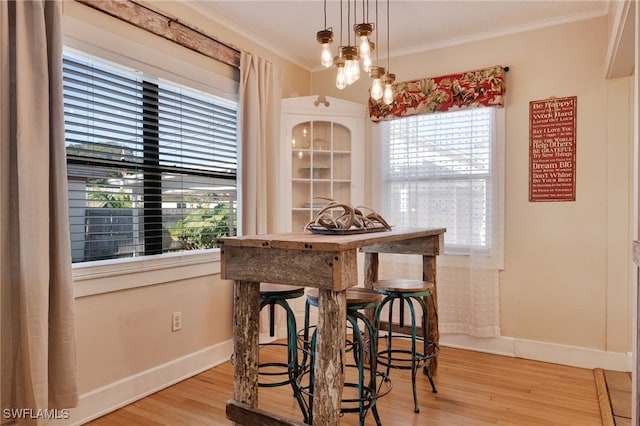 dining room with crown molding, a healthy amount of sunlight, and light wood-type flooring