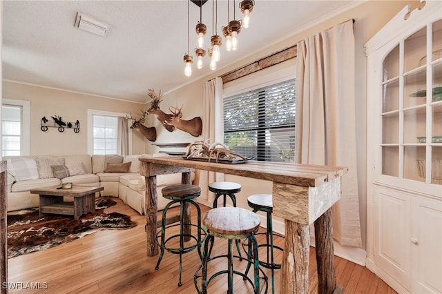 dining space featuring light wood-type flooring, crown molding, and a wealth of natural light