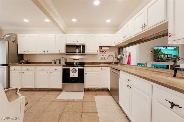 kitchen with sink, beamed ceiling, light tile patterned flooring, white cabinets, and appliances with stainless steel finishes