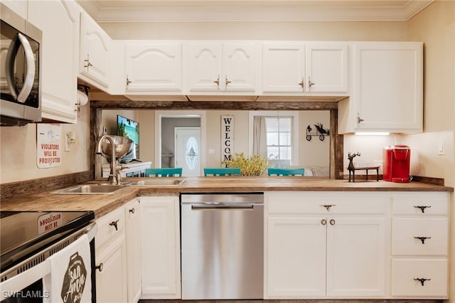 kitchen with white cabinets, sink, ornamental molding, and stainless steel appliances